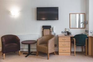 um quarto com duas cadeiras e uma mesa e uma televisão em Wycliffe Hotel em Stockport