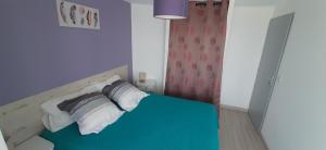 een slaapkamer met een bed met blauwe lakens en kussens bij LE GERLE in Mercurol