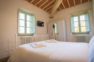 a white bed sitting in a bedroom next to a window at Il Podere Degli Artisti in San Casciano dei Bagni