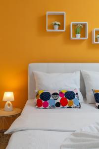 a bedroom with a white bed with an orange wall at Apartments Villa Zrinka in Rogoznica