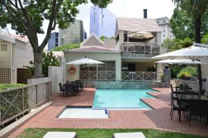 ein Haus mit einem Pool mit Tischen und Stühlen in der Unterkunft Courtyard Hotel Sandton in Johannesburg