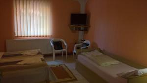 a room with two beds and a table and a tv at Sobe Rooms Szobák Zimmer KIS in Palić