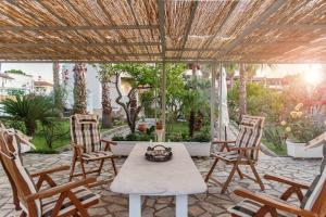 um pátio com uma mesa e cadeiras e vista para um jardim em Christa Luxury Apartments em Kavos