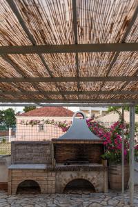 a stone fireplace in a patio with a wooden roof at Christa Luxury Apartments in Kavos