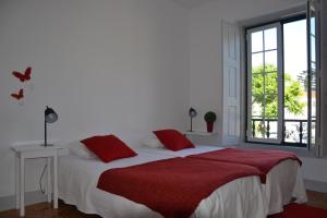 a bedroom with a bed with a red blanket and a window at Hostel Rossio Alcobaça in Alcobaça