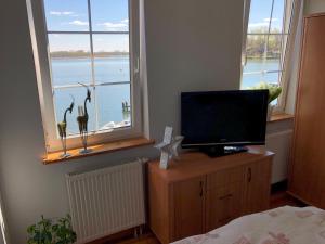 a bedroom with a bed and a television and a window at Przystań Stary Folwark in Stary Folwark