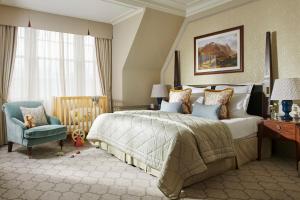 a bedroom with a large bed and a blue chair at The Gleneagles Hotel in Auchterarder