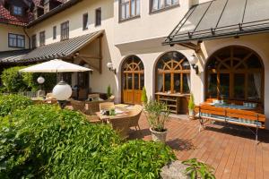 un patio con tavoli, sedie e ombrellone di Hotel Hoyacker Hof a Garching bei München