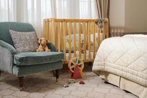 a teddy bear sitting in a chair next to a crib at The Gleneagles Hotel in Auchterarder