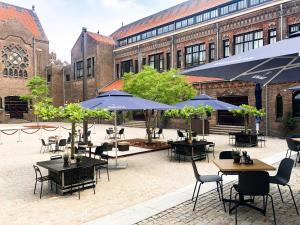 a patio with tables and umbrellas in front of a building at Mariënhage Boutique Hotel in Eindhoven