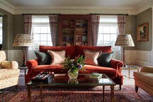 a living room with a red couch and a table at The Gleneagles Hotel in Auchterarder