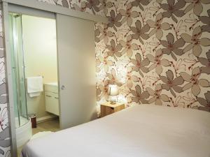 a bedroom with a bed and a flowery wallpaper at Hôtel La Villa Lorraine in Toul +37 photos