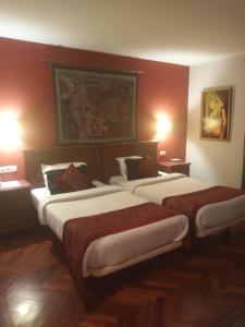 two beds in a hotel room with red walls at Hotel Kerala in San Esteban de Pravia