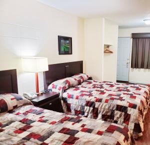 Habitación de hotel con 2 camas y mesa con lámpara en Canadian Motor Inn, en Grande Prairie