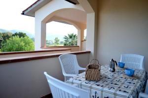 a table with white chairs and a window at Appartamenti Casa Dini in Marina di Campo