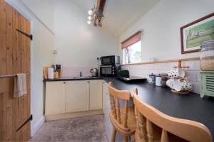 a kitchen with a black counter top and wooden chairs at The Nook at West Langton lodge in Market Harborough