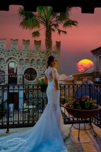 kobieta w sukni ślubnej stojąca przed zachodem słońca w obiekcie Residenza L'Antico Borgo Hotel w mieście Filadelfia