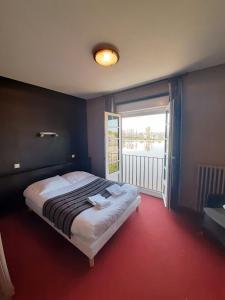 a bedroom with a large bed and a large window at Hôtel Restaurant du Lac in Combourg