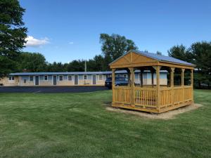 a wooden gazebo in a field in front of a building at Pine Ridge Motel in Dodgeville