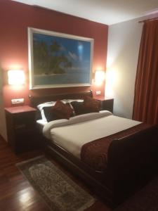 ein Schlafzimmer mit einem Bett und zwei Lampen und ein Gemälde an der Wand in der Unterkunft Hotel Kerala in San Esteban de Pravia