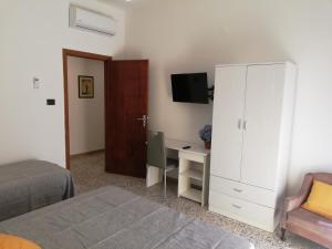 Schlafzimmer mit einem Bett, einem Schreibtisch und einem weißen Schrank in der Unterkunft Appartamento City in Palmi
