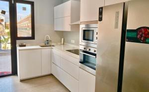 uma cozinha com armários brancos e um frigorífico em CHALET CON PISCINA PRIVADA EN LA URB. DE PUERTO REY em Los Amarguillos