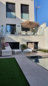 - une terrasse avec des chaises et un parasol à côté d'un bâtiment dans l'établissement CHALET CON PISCINA PRIVADA EN LA URB. DE PUERTO REY, à Los Amarguillos