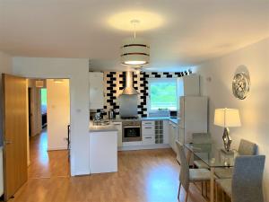 a kitchen with white appliances and a glass table at Firpark City Apartment - 2 Bedrooms in Glasgow