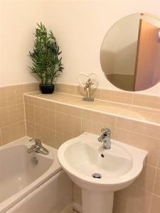 a bathroom with a sink and a mirror and a tub at Firpark City Apartment - 2 Bedrooms in Glasgow