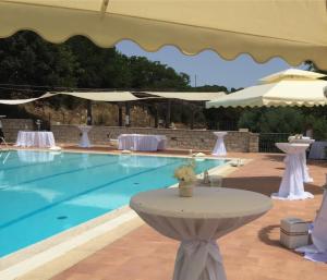 a swimming pool with a table and an umbrella at Hotel Ristorante Gusana in Gavoi