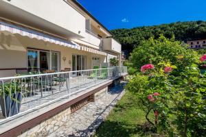 ein Haus mit einem Balkon mit Tischen und Stühlen in der Unterkunft Apartments Rosovic J&C in Mošćenička Draga