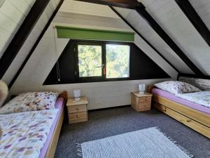 a attic room with two beds and two windows at Ferienhaus Rhode am Alfsee in Rieste