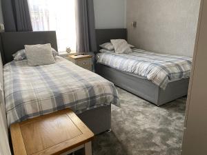 1 dormitorio con 2 camas y mesa de madera en Inglewood Guest House en Sandown