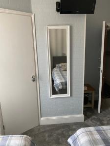 um espelho numa parede com uma cama num quarto em Inglewood Guest House em Sandown