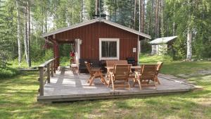 a cabin with chairs and a table on a deck at Kaijonselän mökit Pyhitty in Vehmaskylä