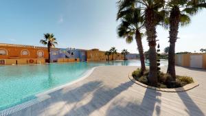 een groot zwembad met palmbomen en gebouwen bij Duplex Mandala 2 Moraira in Benitachell