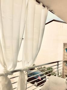 a window with white curtains on a balcony at Sweet & cosy room next to the beach in Viareggio