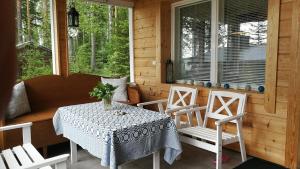 - une table et des chaises sur la terrasse couverte d'une cabine dans l'établissement Kaijonselän mökit Pyhitty, à Vehmaskylä