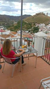 een persoon aan een tafel op een balkon bij Hostal Durán in Alora