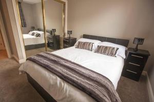 een slaapkamer met een groot bed en een grote spiegel bij City Centre Executive 2 Bed Apartment with WiFi & Parking in Aberdeen