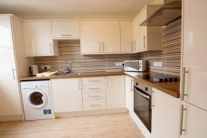 een keuken met witte kasten en een wasmachine en droger bij City Centre Executive 2 Bed Apartment with WiFi & Parking in Aberdeen