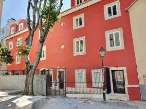 a red building with a tree in front of it at Casa das Olarias in Lisbon