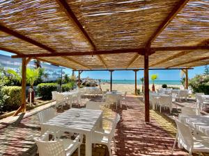 un patio con tavoli e sedie bianche e la spiaggia di Hotel Enera a Golem