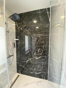 a bathroom with a shower with a black marble wall at Jurmala Guest House Markiza in Jūrmala