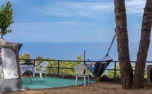 una hamaca colgada de un árbol junto a dos sillas en Camping Roca Grossa, en Calella