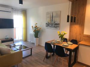 - un salon avec une table, des chaises et des fleurs dans l'établissement Apartament Słoneczny z klimatyzacją i garażem, à Toruń