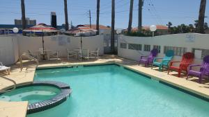 una gran piscina con sillas, mesa y sillas en South Padre Island Inn, en South Padre Island