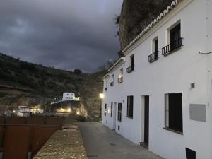 une rue avec des bâtiments blancs et une montagne dans l'établissement Apartamentos3Cuevas, à Setenil de las Bodegas