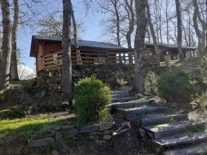 eine Blockhütte im Wald mit einer Steinmauer in der Unterkunft La Albarina in Galende