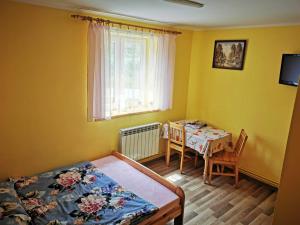 a room with a bed, table and window at Pokoje nad strumykiem w Polanczyku in Polańczyk